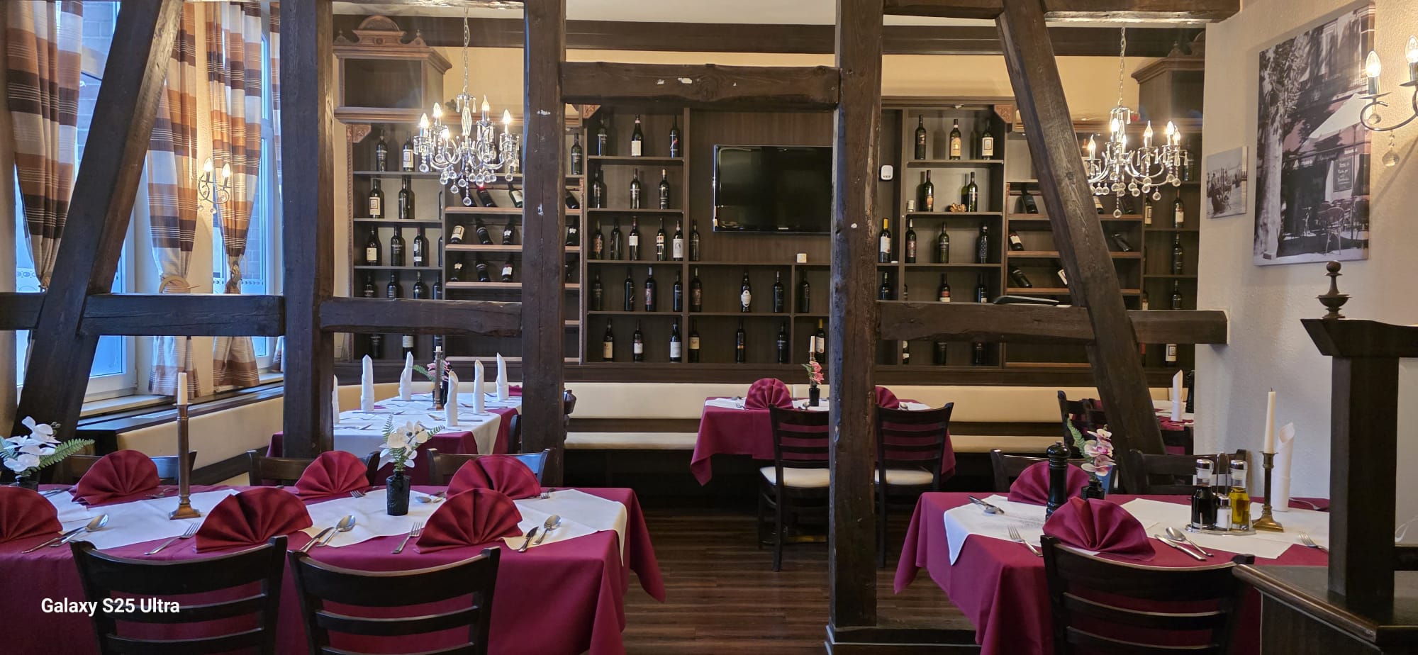 Gut gefülltes Weinregal an dunkler Holzwand im Ristorante Paganini